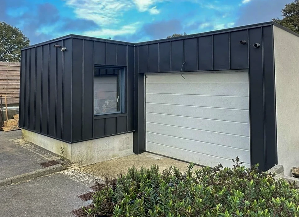 Vue aérienne d'une toiture métallique verte à bacs acier nervurés, montrant plusieurs pans de toit avec arêtiers et noues