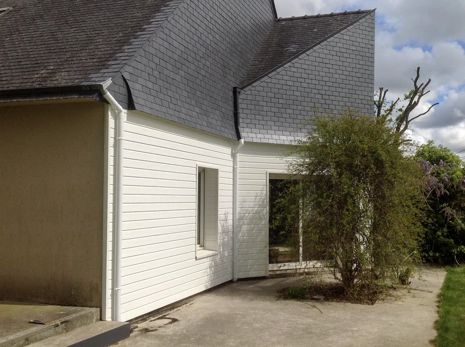 Extérieur d'une maison avec toiture métallique grise à joints debout et lucarne ouverte