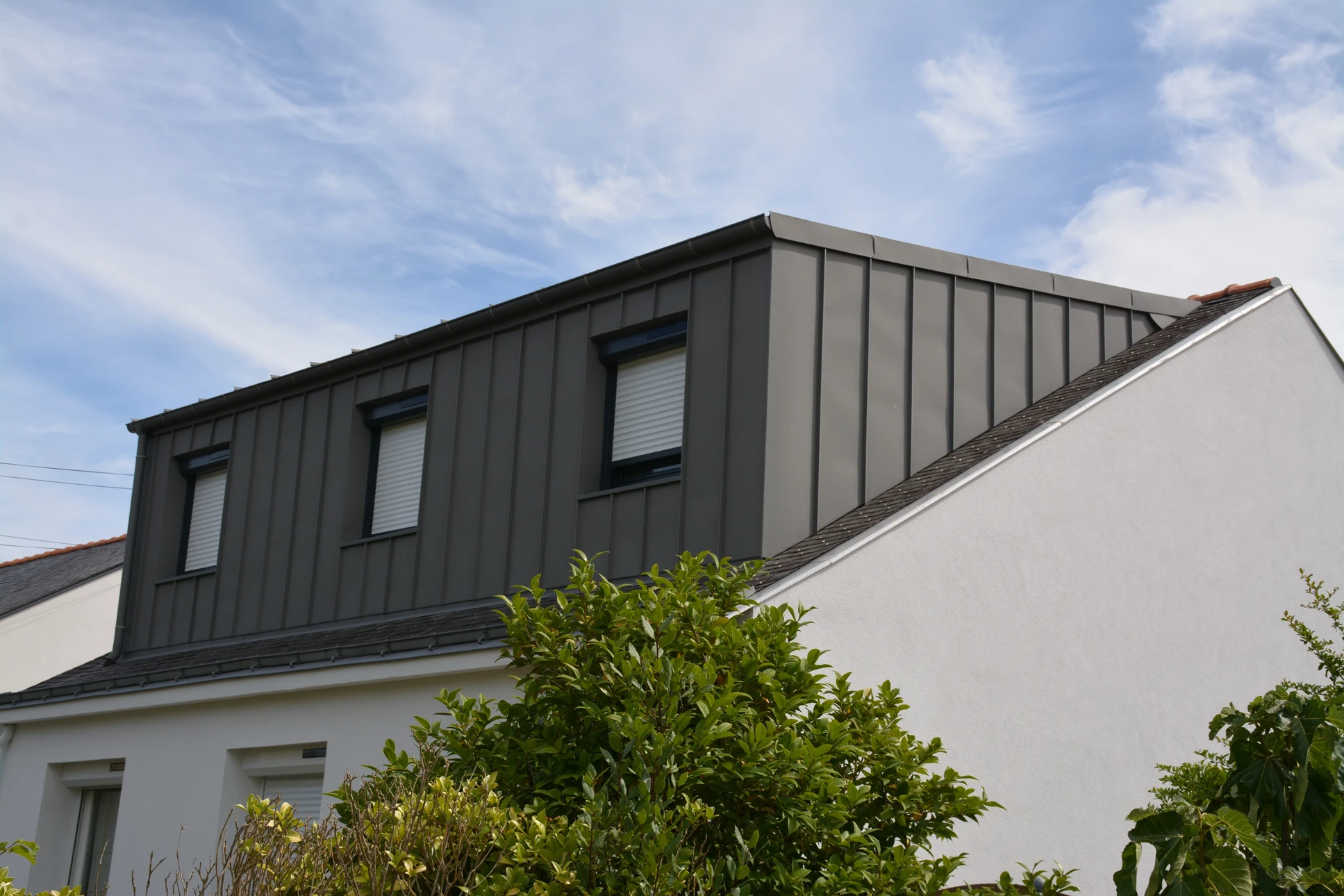 Chantier de construction résidentielle en cours, structure bois lamellé-collé avec charpente apparente et couverture zinc joint debout