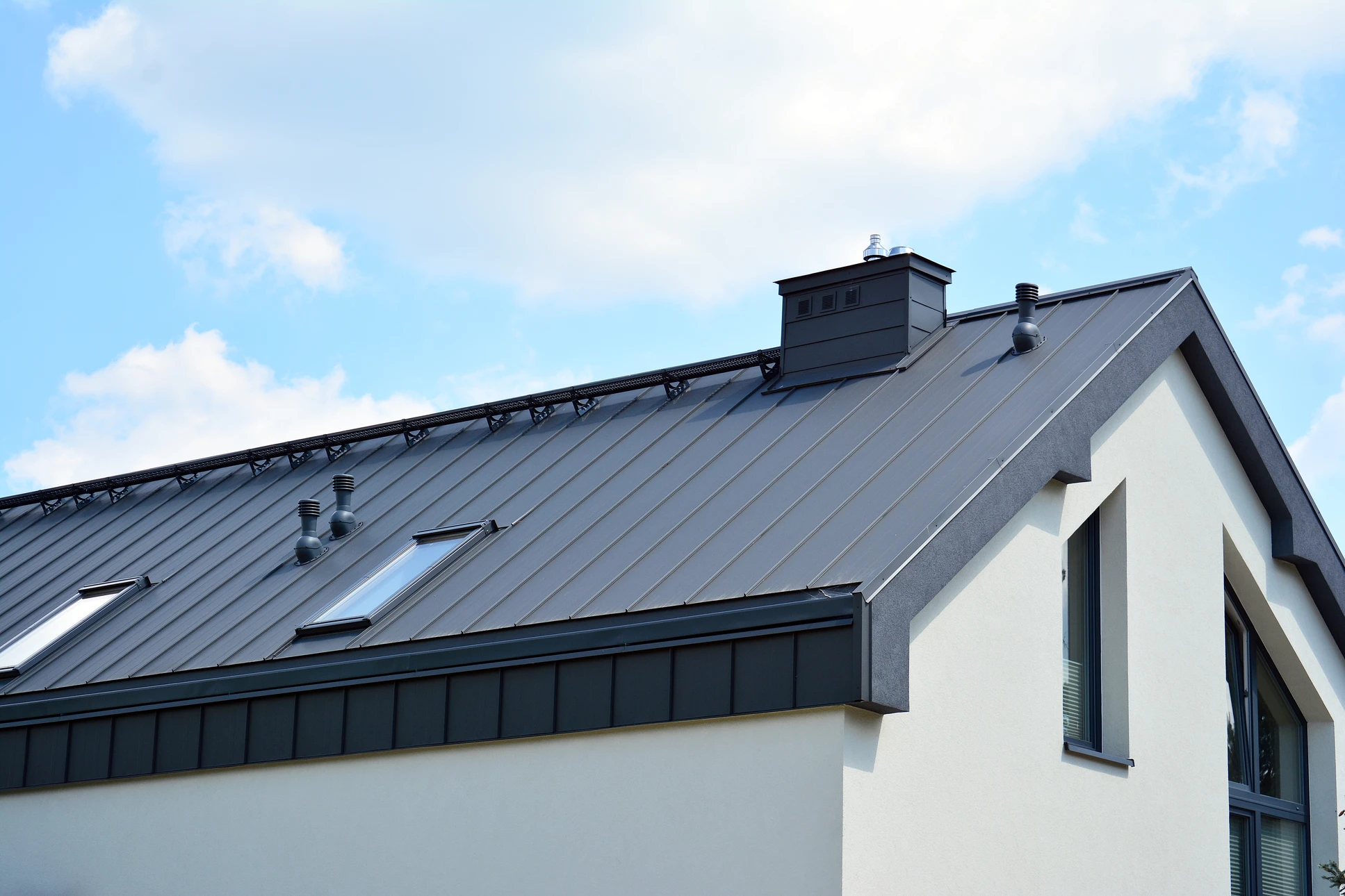 Ouvrier couvreur en silhouette travaillant sur une toiture en pente contre un ciel bleu nuageux